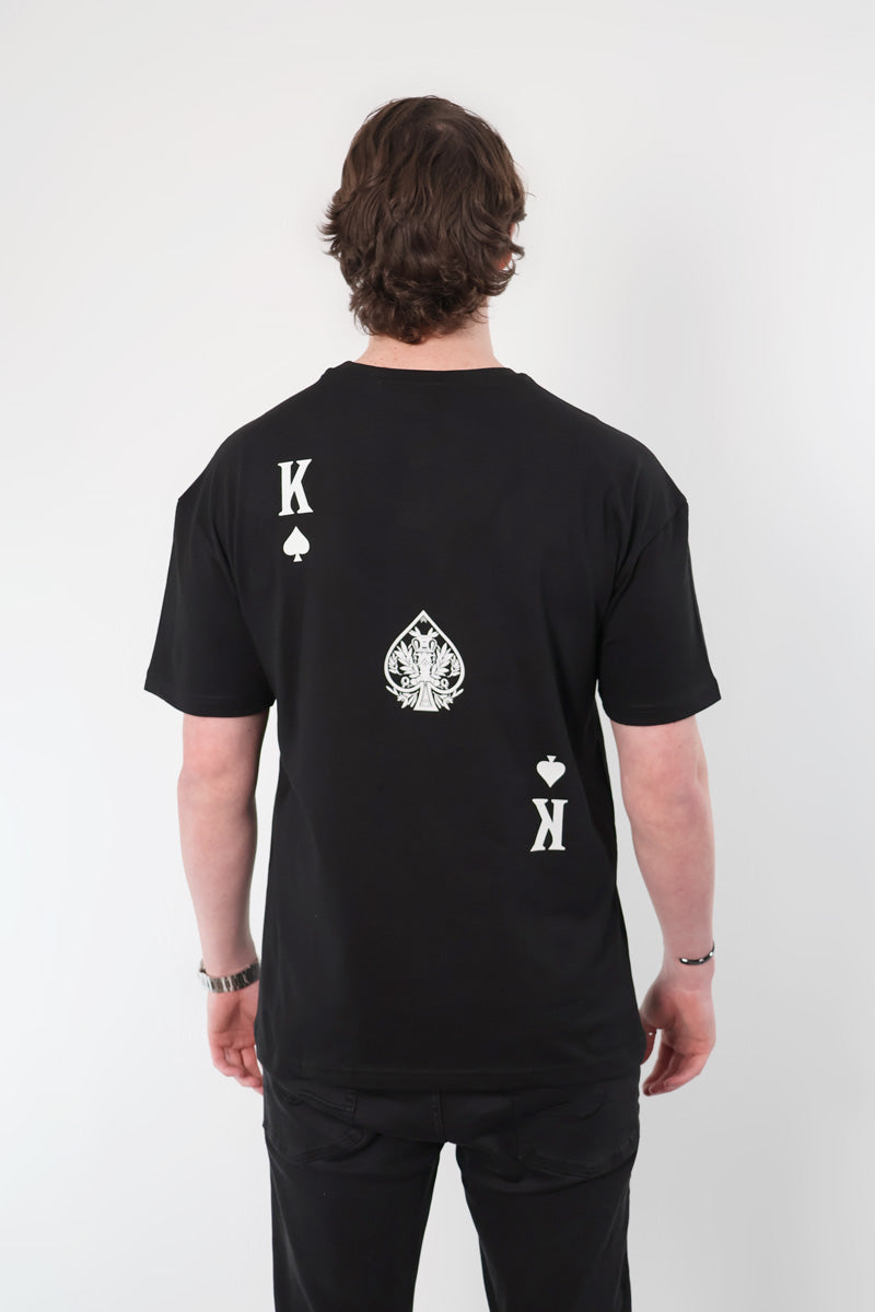 An individual wearing the Olympian Royale Oversized T-Shirt featuring a king of spades card design on the back.