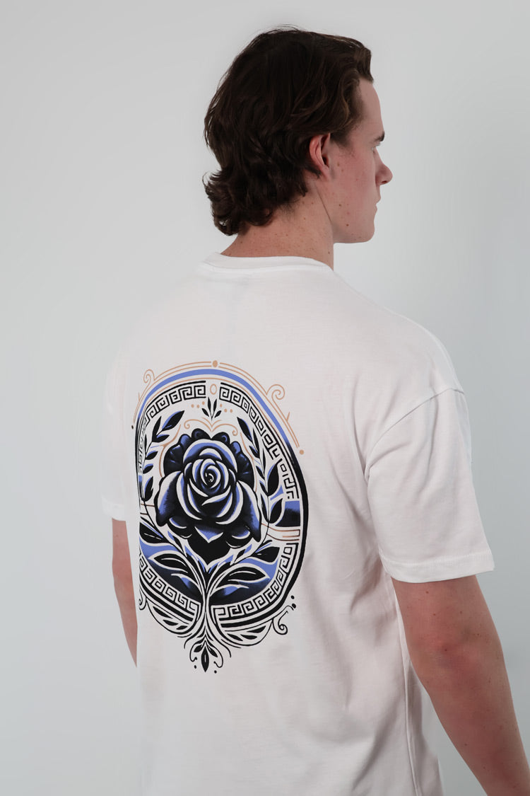 Person wearing the Aegean Rose T-Shirt, which features a white base with a blue and black rose design and ornate patterns on the back.
