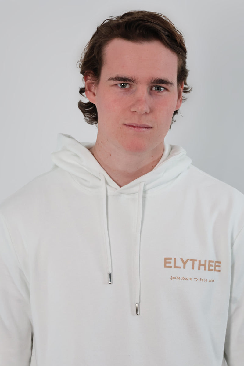 A person with short brown hair is wearing the Eternal Laurel Hoodie - Unisex, featuring ELYTHEE printed on it, against a plain light gray background.