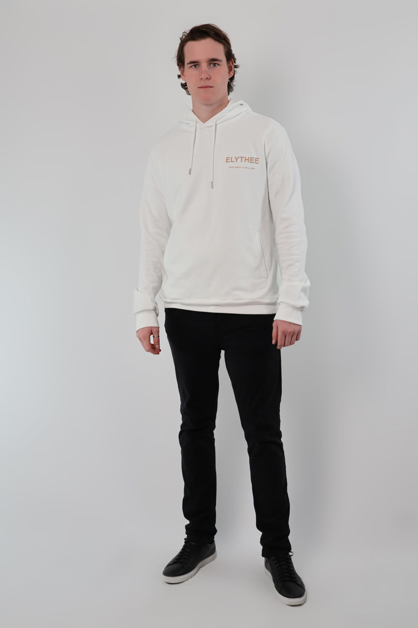 A person is standing against a plain background, wearing the Eternal Laurel Hoodie in white with ELYTHEE text, paired with black pants.