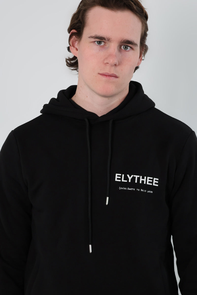 A person wearing the Mythos Essence Hoodie, featuring ELYTHEE printed on the front.