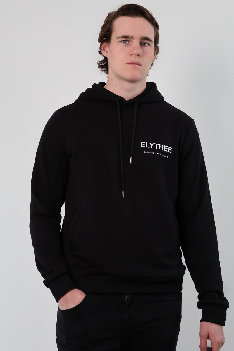 A person wearing the Mythos Essence Hoodie in black featuring ELYTHEE on the front, stands against a plain background.