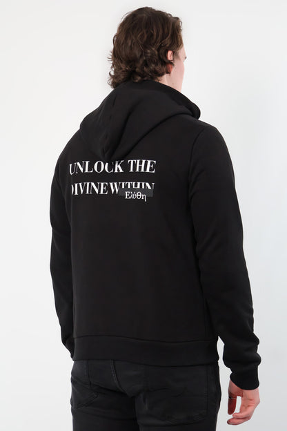 A person in a Mythos Essence Hoodie, featuring Unlock the divine within on the back, stands against a white background.