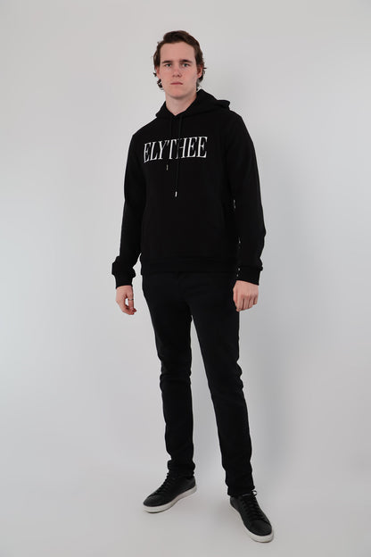 Against a plain white background, a person wears a sleek black unisex Nectar Nomad Hoodie, paired with matching pants.