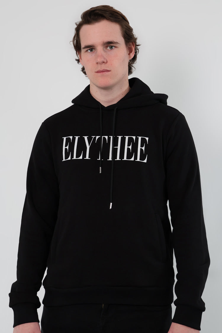 A person wearing a Nectar Nomad Hoodie, the classic unisex staple, stands against a plain backdrop. ELYTHEE is boldly emblazoned across their black hoodie, capturing attention with its minimalist appeal.