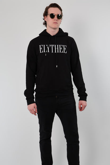 A person wearing sunglasses and a black unisex Nectar Nomad Hoodie stands against a plain light background, embodying the essence of understated style.