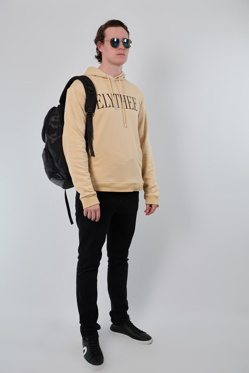 Wearing a Nectar Nomad Hoodie with sunglasses, someone pairs it effortlessly with black pants and sneakers. Holding a black backpack, they stand against a plain backdrop, perfectly blending casual style and sophistication.