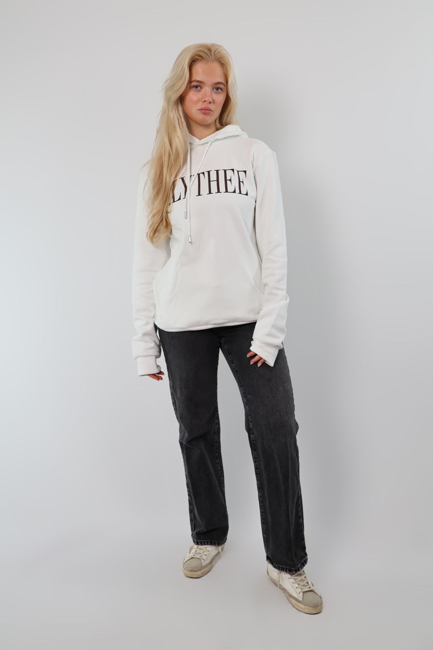 A person is sporting a white Nectar Nomad Hoodie with LYTHEE text, paired with black jeans and white sneakers, standing against a plain background.