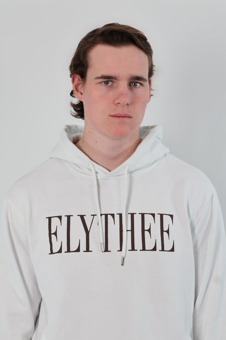 A person wearing the unisex Nectar Nomad Hoodie, featuring ELYTHEE prominently on the front, looks confidently at the camera against a plain background.