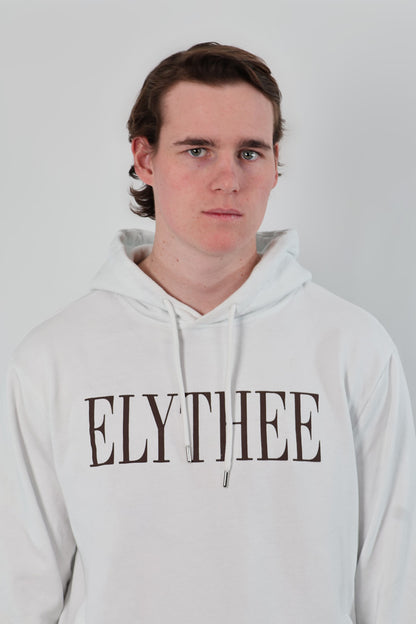 A person wearing the unisex Nectar Nomad Hoodie, featuring ELYTHEE prominently on the front, looks confidently at the camera against a plain background.