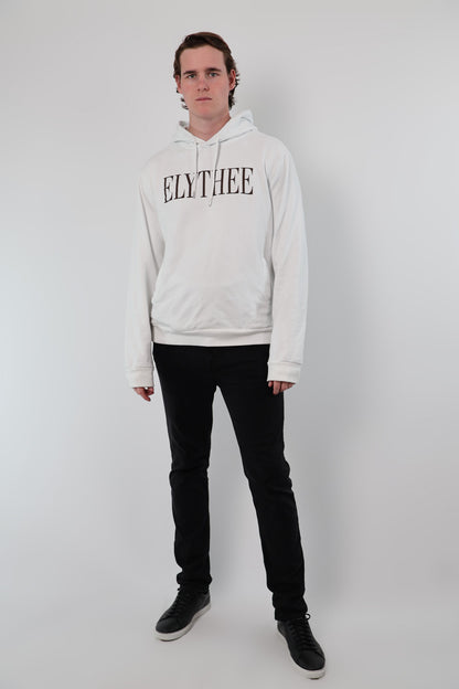 A person wears a white Nectar Nomad Hoodie with ELYTHEE prominently printed, paired with black pants, standing against a plain backdrop, effortlessly showcasing the unisex hoodie style.